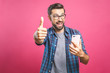 © denis_vermenko - Portrait of a cheerful bearded man taking selfie and showing thumbs up gesture over pink background. Isolated.