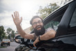 Cheerful man waving while driving a car