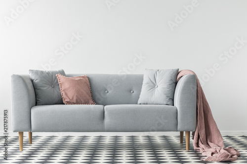 Pink Blanket On Grey Couch With Pillows On Checkered Floor In