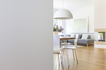 Lamp above table and chairs in apartment interior with wooden floor and copy space. Real photo