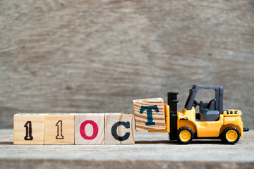 Wall Mural - Toy forklift hold block T to complete word 11 oct on wood background (Concept for calendar date in month October)