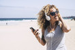 beautiful middle age caucasian lady enjoy the freedom and the fun of a vacation at the beach in tropical island and nice resort. smile and look at the sun listening music with the smart phone