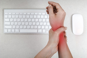 A woman feels a pain in her wrist using her computer mouse. 