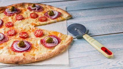 Pizza with salami and cheese on a wooden light background. Close-Up