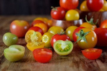 Poster - Assortment of multicoloured whole and cut tomatoes on a wooden table