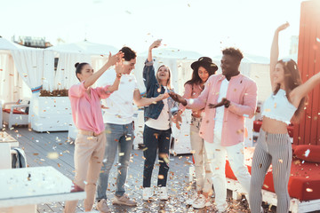 Positive females and cheerful men dancing while entertaining together outside. Glad friends during celebration concept