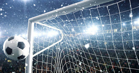 Wall Mural - Photo of the ball that flies into a goal on a professional soccer stadium while it's snowing