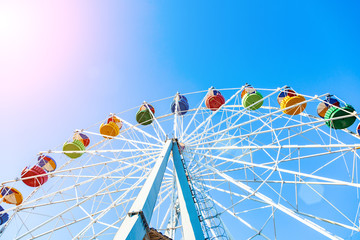 Colorful ferris wheel of the amusement park in the blue sky background