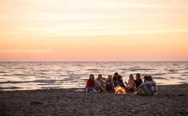 Group Of Young Friends Sitting By The Fire at beach