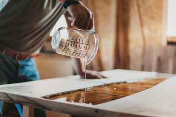 Detail of Skilled Artisan Carpenter Working on a Piece of Furniture with Epoxy Resin in his Workshop