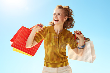 Wall Mural - woman with shopping bags looking into distance against blue sky