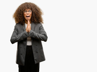 Canvas Print - African american business woman wearing glasses begging and praying with hands together with hope expression on face very emotional and worried. Asking for forgiveness. Religion concept.