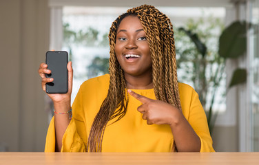 Wall Mural - African american woman using smartphone very happy pointing with hand and finger