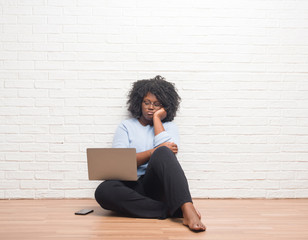 Canvas Print - Young african american woman sitting on the floor using laptop at home thinking looking tired and bored with depression problems with crossed arms.