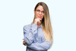 © Krakenimages.com - Beautiful young woman wearing elegant shirt and glasses looking confident at the camera with smile with crossed arms and hand raised on chin. Thinking positive.