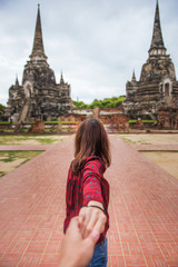 Wall Mural - Woman in red shirt leading man by hand to the Wat Phra Si Sanphet famous temple in Ayutthaya, Thailand.