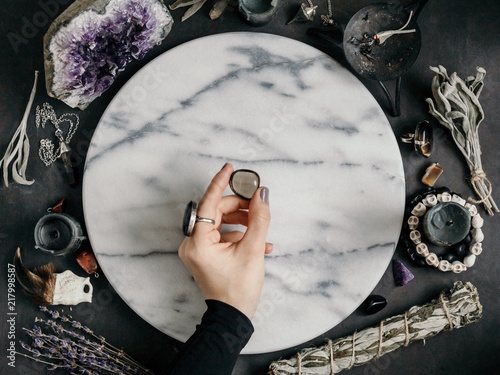 Fotografie, Obraz Witch's hand holding Smoky quartz above a marble white round tray