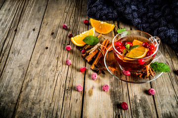 Autumn winter hot drink, cranberry spicy tea with orange, cinnamon and anise. On an old wooden background, with a warm blanket, copy space for text