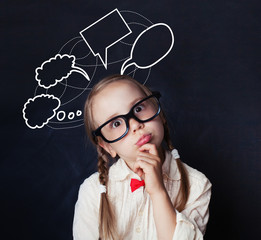 Portrait of funny little girl with empty speech clouds chalk drawing on blackboard background