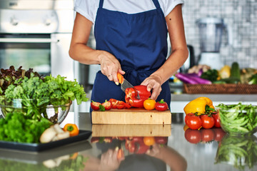 Housewife cutting vegetables on salad in kitchen.