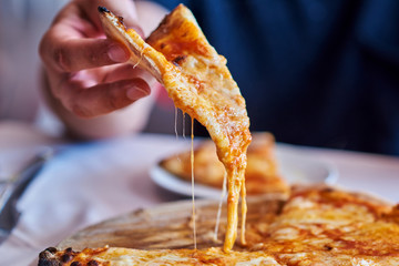 Hot pizza slice with melting cheese.  Lunch or dinner  delicious food italian traditional on wooden table  in side view. Close up Italian pizza with cheese it stick. Selective focus.