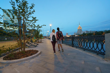 People walking at the sunset in city embankment