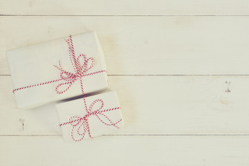 Vintage gift boxes on the shabby wooden background. Gift box wrapped white paper,  tied red & white baker twine with tag. Vintage Style. Background for your design. Holiday packing concept.