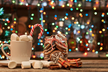 Wall Mural - Cup of coffee with cinnamon and dried orange on a Christmas light background.