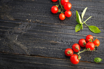 Red cherry tomatoes on black wooden background