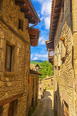 Wall Mural - Beautiful view of scenic narrow alley with historic traditional houses and cobbled street in an old town in Europe with blue sky and clouds in summer with retro vintage