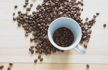 Coffee beans in a coffee cup on wooden background.