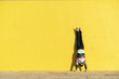 © Westend61 - Acrobat doing handstand in front of a yellow wall