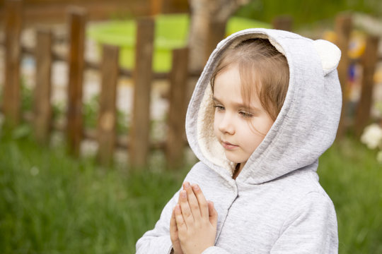 girl prays to God in a garden on a background of spring greens