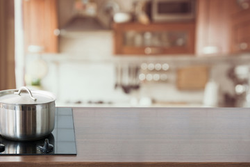 Wall Mural - Blurred and abstract kitchen background. Wooden tabletop with pan and defocused modern kitchen.