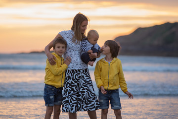 Canvas Print - Young mother with her beautiful children, enjoying the sunset over the ocean on a low tide in Devon