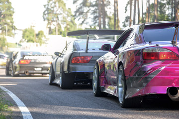 Drift cars standing at the start line, waiting for race to begin. Rally car warming up the tires, blue smoke all around  
