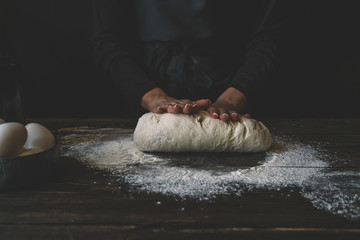 View of baker kneading dough. Homemade bread. Hands preparing bread dough on wooden table. Preparing traditional homemade bread. Woman hands kneading fresh dough for making bread.