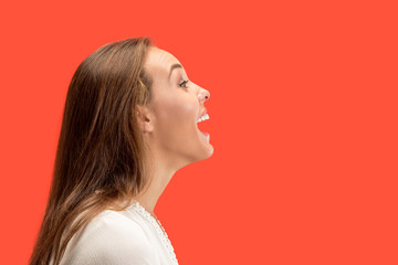 Wall Mural - Happy business woman standing and smiling isolated on red studio background. Beautiful female half-length portrait. Young emotional woman. The human emotions, facial expression concept. Profile view.