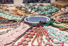 Gemstone Bracelets And Necklaces Made Of Malachite, Rose Quartz, Larimar, Mahogany Obsidian, Unakite, Amethyst, Chalcedony, Green Jasper Stones And Crystals Laying On Linen Tablecloth Around Mirror
