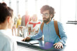 © pressmaster - Bearded adult man checking in and talking to staff at reception in airport