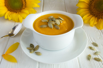 Wall Mural - Soup with pumpkin  in the plate on the white wooden background