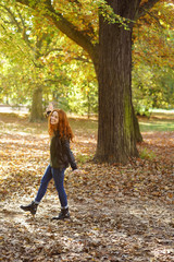 Poster - Young smiling woman walking in park on autumn day