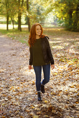 Poster - Red-haired smiling woman walking in park