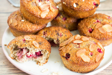 Raspberry muffins with almond on top served on white plate