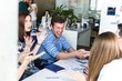 © pantovich - Colleagues shake hands sitting at a table in the office laughing and rejoicing
