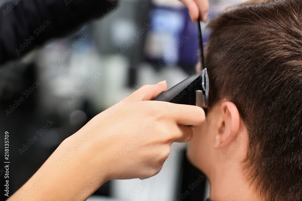 Professional stylist cutting client's hair in salon, closeup