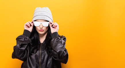 fashionable woman with attitude in bomber jacket and sunglasses on a yellow background