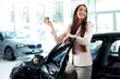 © zorandim75 - Happy woman holding keys to her new car at the dealership