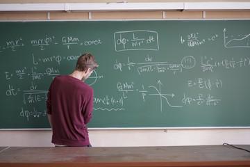 young student in casual writing physics formula on the blackboard during study course