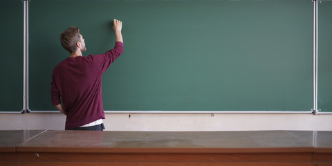 young student in casual writing physics formula on the empty blank blackboard during study course copy space mock up
